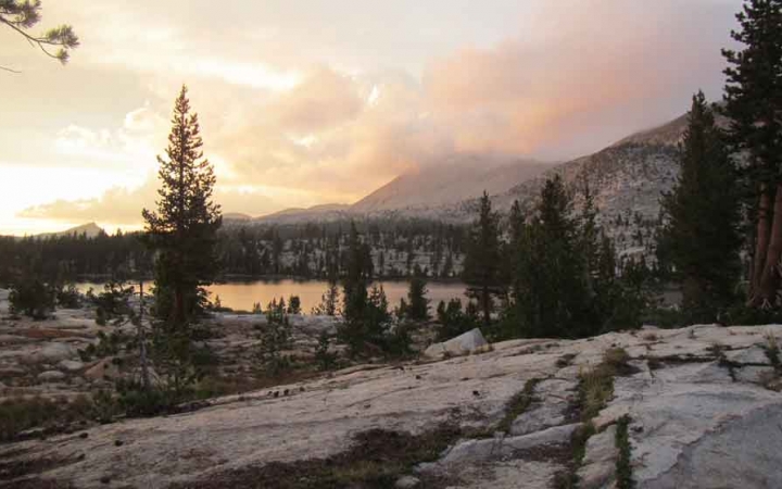 a body of water lies among trees and hills in yosemite